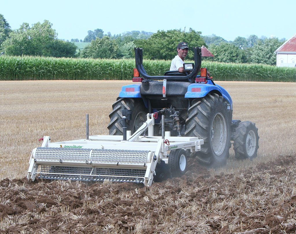 GroundBuster brand tiller pulled in field by tractor